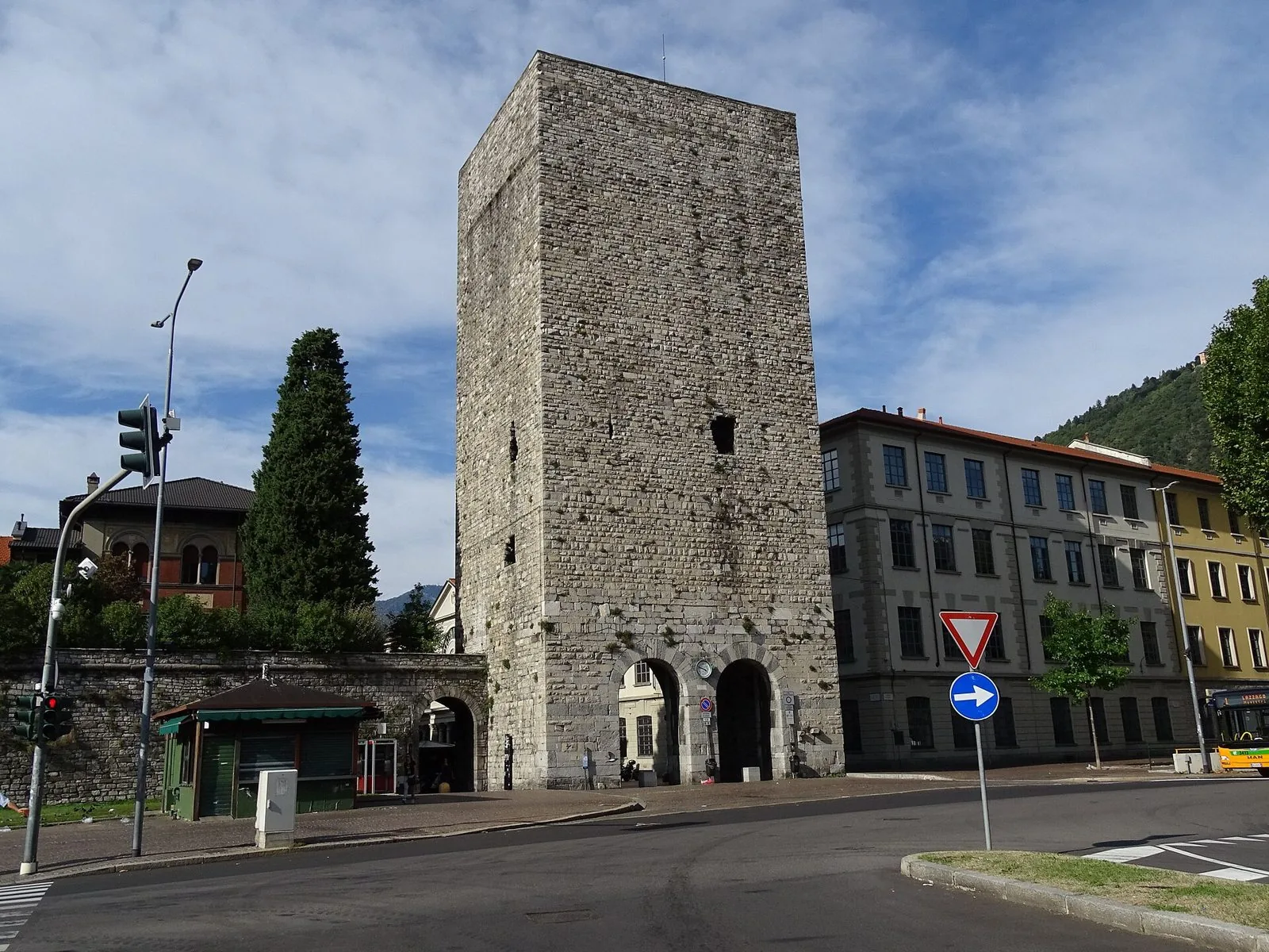 Porta Torre a Como: la torre medievale in pietra a pianta quadrata con i due archi d'ingresso, accanto a un tratto delle mura